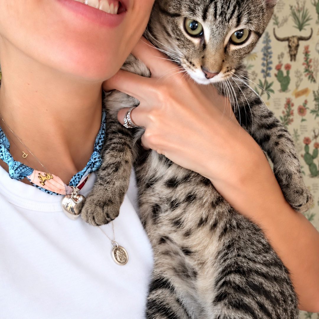 Jess, founder of It’s Just Jess, wearing one of her hand-tied silk scarf necklaces with silver heart pendant and holding her cat