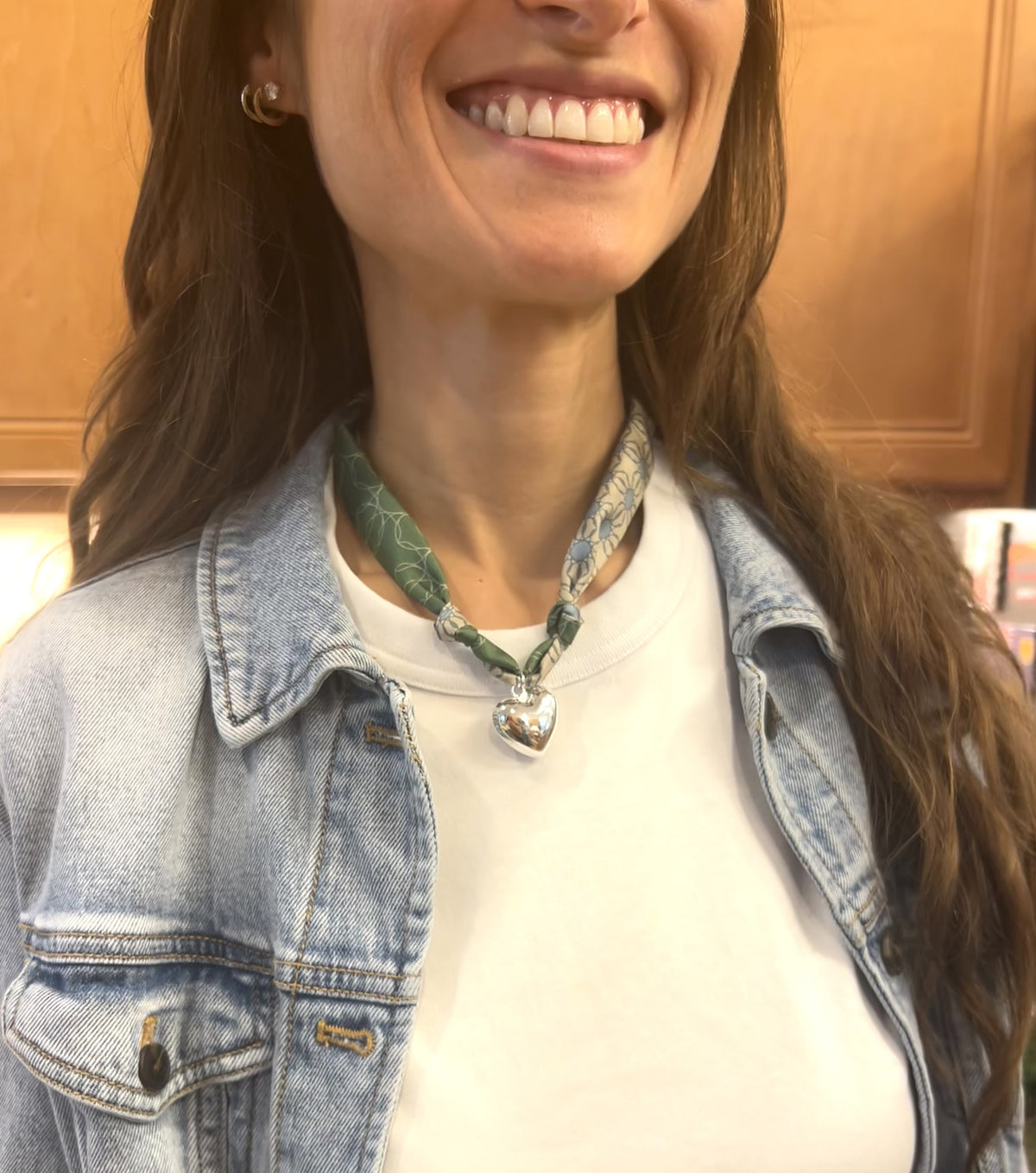 Woman wearing The Alma hand-tied silk scarf necklace with silver heart pendant in a white t-shirt and denim jacket