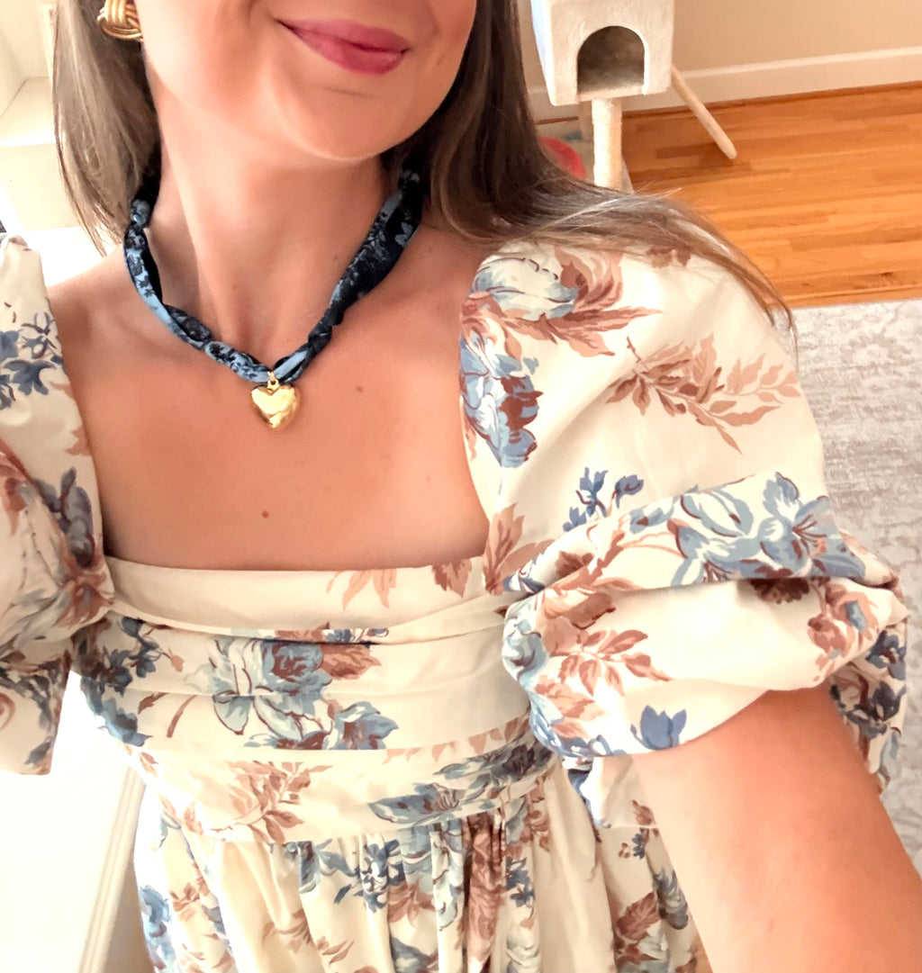 Woman wearing The Andrea silk scarf necklace with a floral dress
