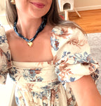 Woman wearing The Andrea silk scarf necklace with a floral dress