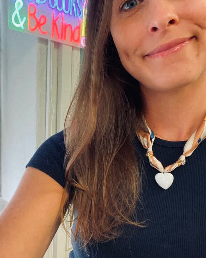 Woman wearing The Angela silk scarf necklace with a black tee shirt