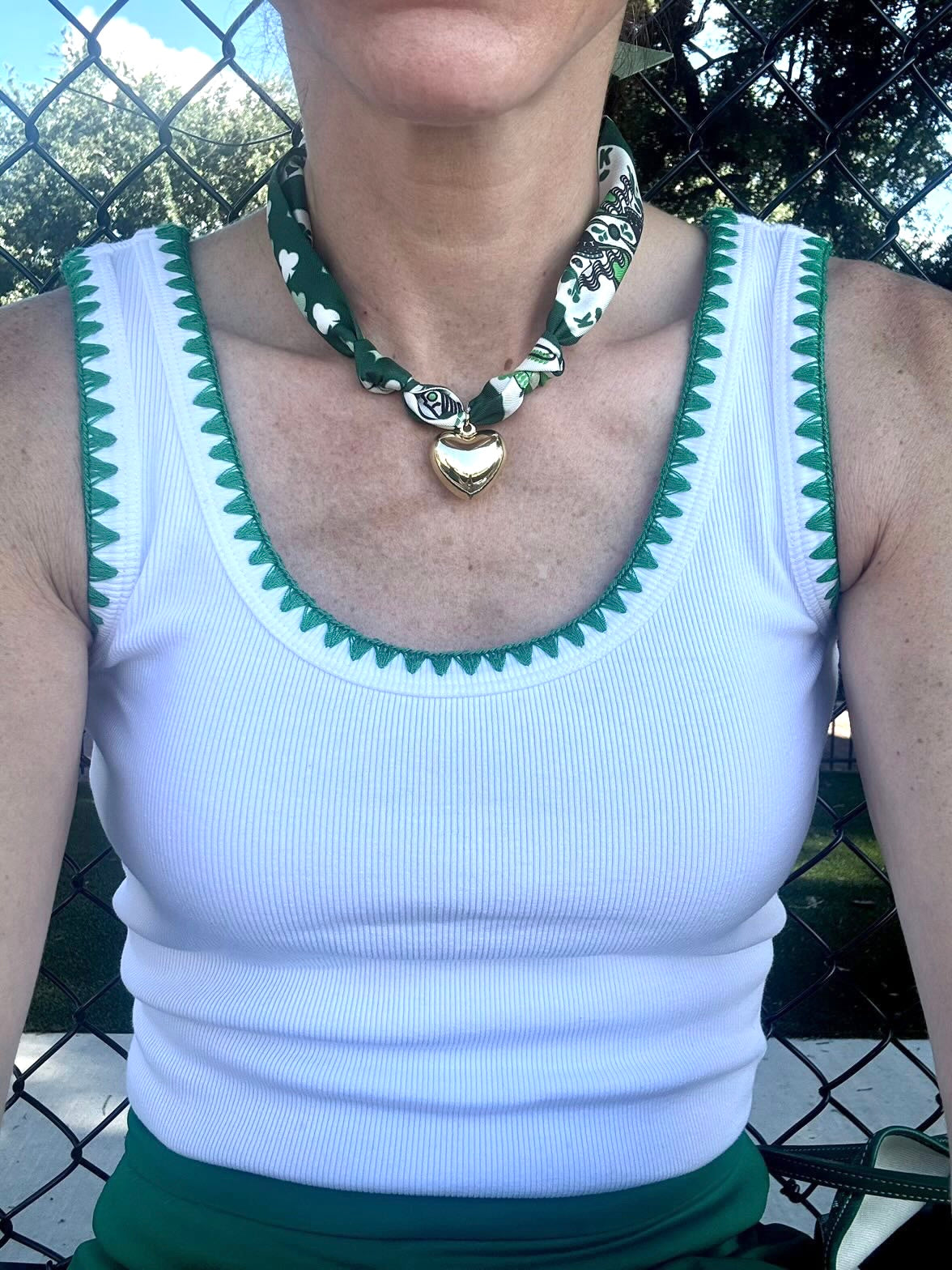 Woman wearing The Britta silk scarf necklace with a white tank top and green border