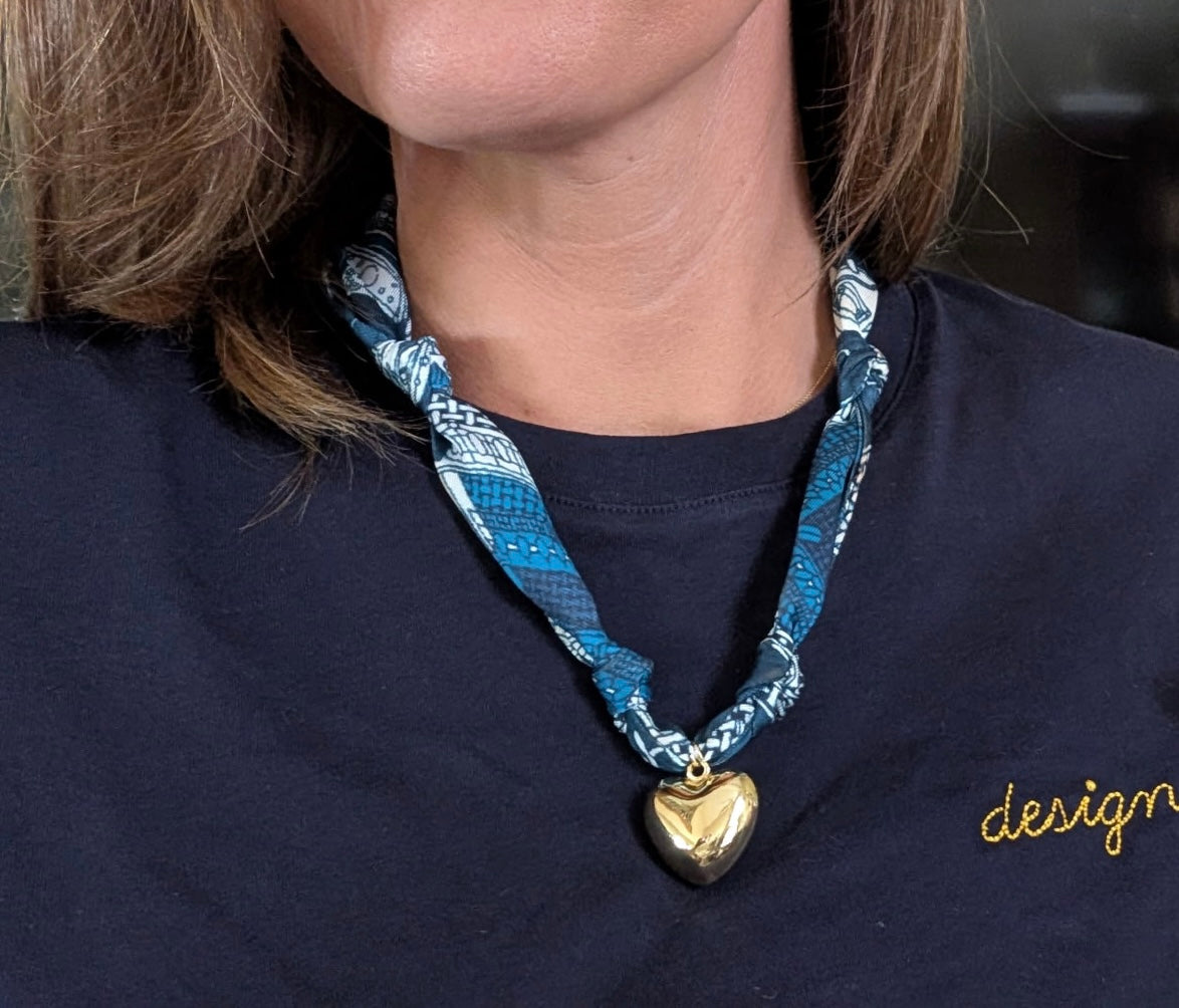 Woman wearing The Haley silk-blend scarf necklace and gold heart pendant with navy blue t-shirt.