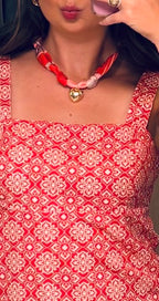 Woman wearing The Jones silk-blend scarf necklace with a red and white print dress