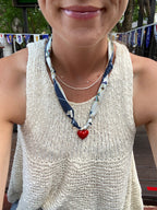Woman wearing the Princess Catherine silk necklace with red heart pendant in a white crochet top