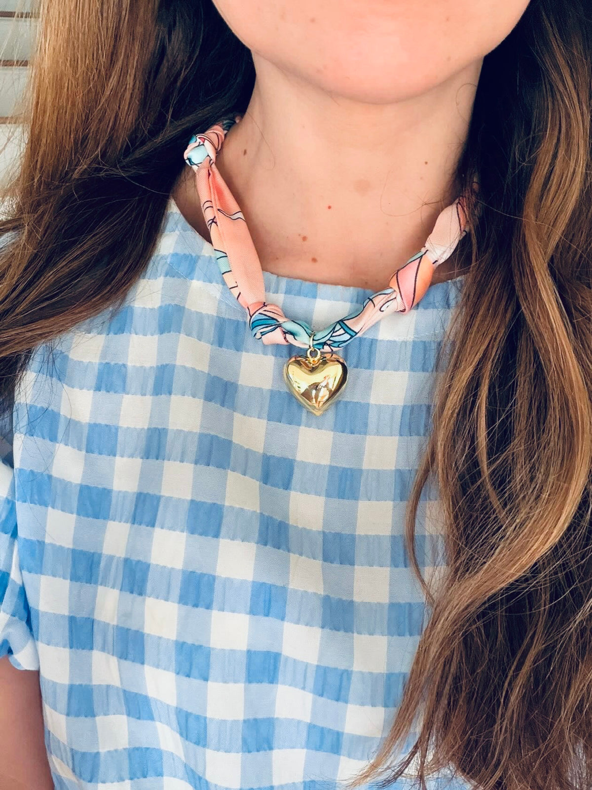 Woman wearing The Sofia silk-blend scarf necklace with a light blue gingham print dress