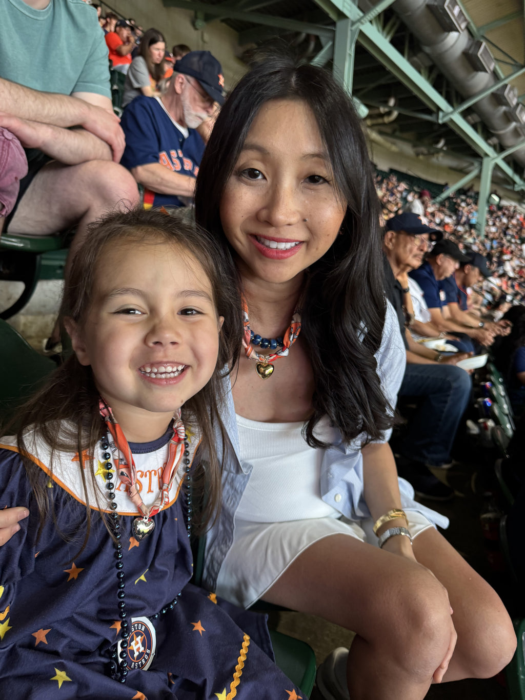 The Gigi scarf necklaces in both original and small size being worn by a mother and daughter at baseball game
