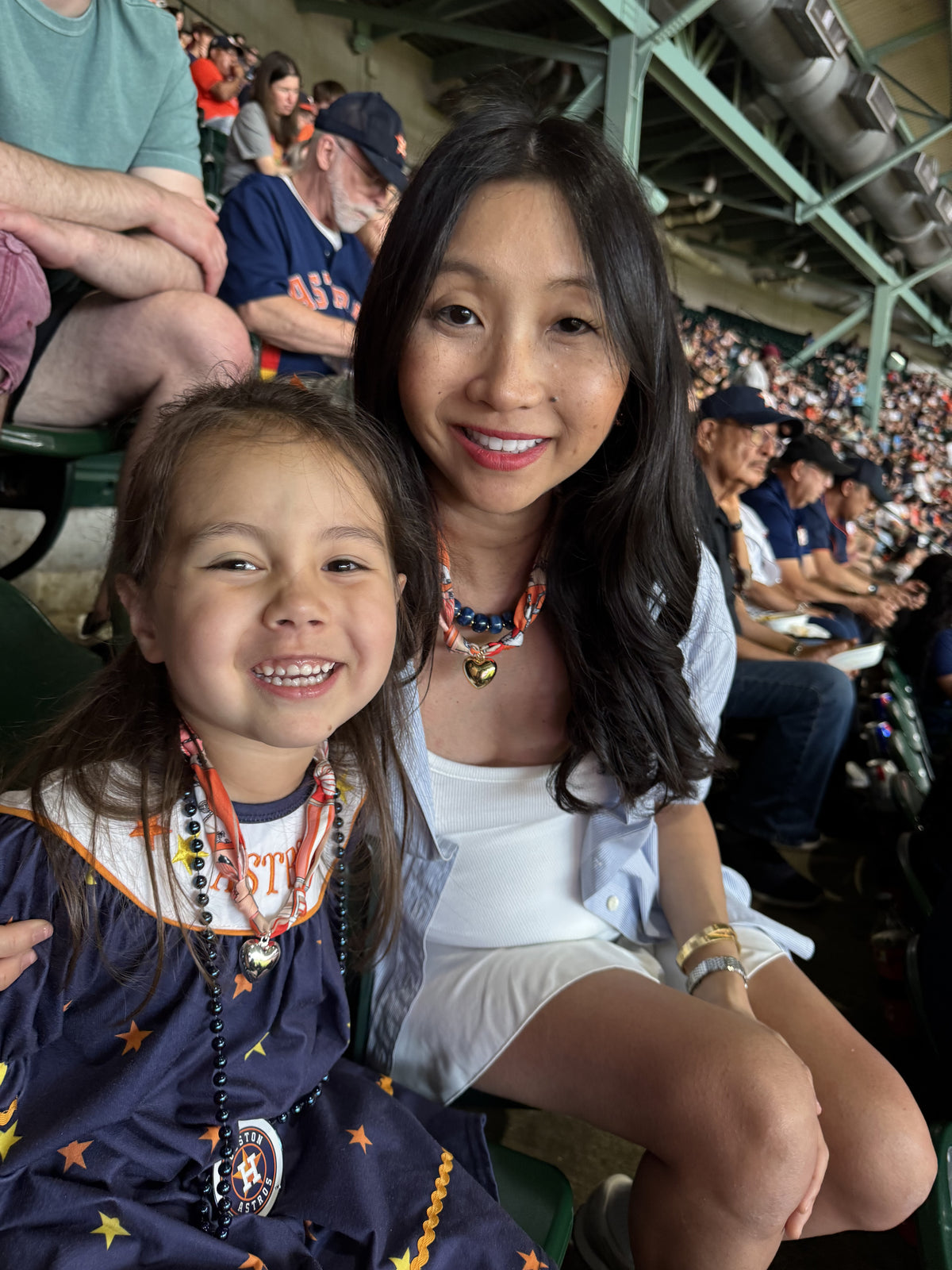 The Gigi scarf necklaces in both original and small size being worn by a mother and daughter at baseball game