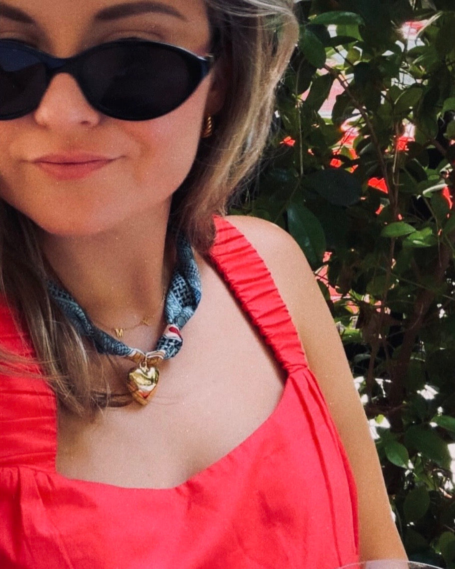 Woman wearing The Sydney silk-blend scarf necklace with a red dress and black sunglasses